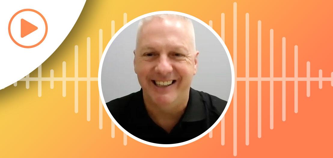 A smiling person with short white hair is centered in a circular frame with a gradient backdrop of yellow and orange, accented by waveform graphics. A white play button sits at the top left, symbolizing innovative strategies to reduce turnover for auto dealers.