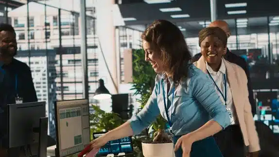 A diverse group of office workers smiling and collaborating in a bright, modern workspace.