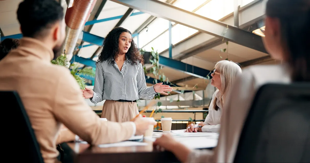 A facilitator leading a group discussion with colleagues around a table