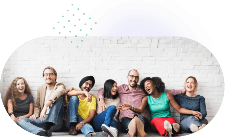 A group of colleagues sitting together against a white brick wall, laughing