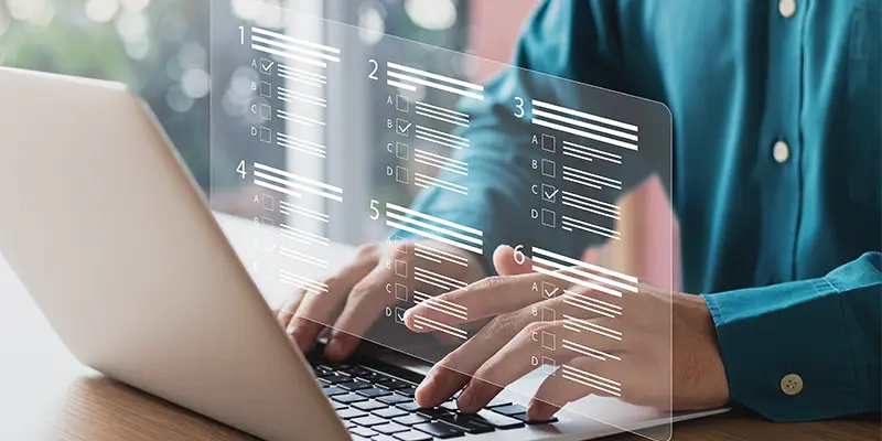 A person types on a laptop with a transparent digital checklist or wonderlic test interface displayed in front of the screen, suggesting online form completion or digital organization.