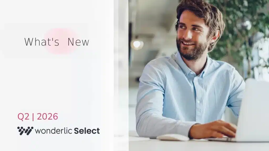 A smiling man in a light blue shirt sits at a desk with a laptop. Text beside him reads, "What's New," highlighting the wonderlic product update June, and at the bottom, "Q2 | 2026 wonderlic Select." The image has a modern, professional feel.