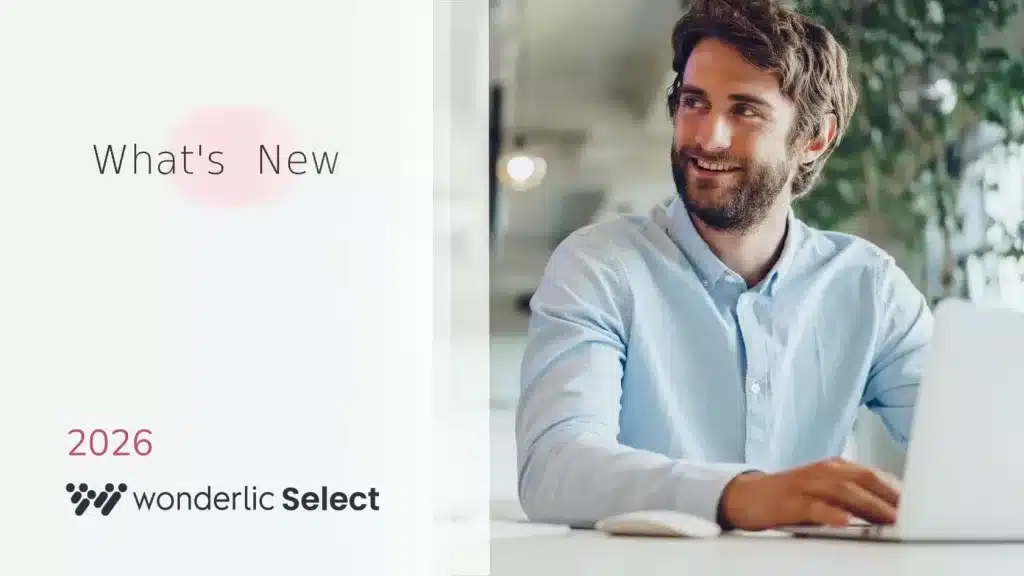 A bearded man in a light blue shirt sits smiling at a desk with a laptop. On the left, text reads "What's New," "2026," and "wonderlic Select." The bright, modern background hints at a wonderlic product update June release.